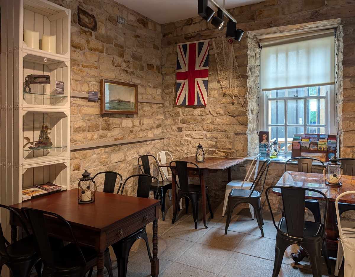 photo of polished wooden tables and metal chairs in a room with sandstone walls and nautical decor.
