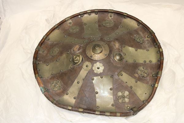 Photo of a round copper coloured shield with silver panels and flower shaped decorations. The rim is scrolled and the centre has a gently tapered conical shape. 
