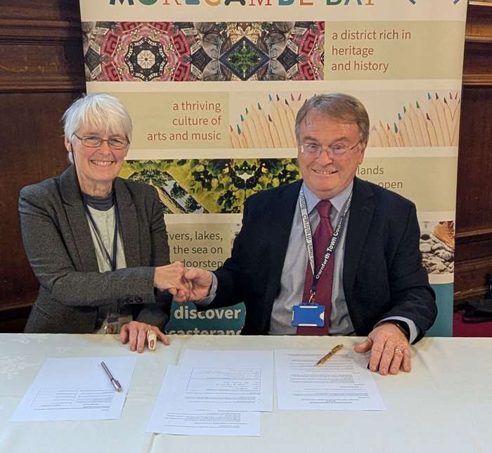 Councillor Caroline Jackson (leader of Lancaster City Council) and Councillor Jim Grisenthwaite (chair of Carnforth Town Council’s Finance & Governance Committee) shake hands after signing the MOU